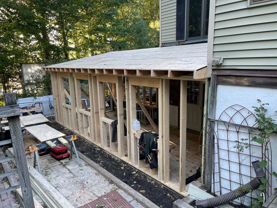 Screened porch framing under construction beside a home