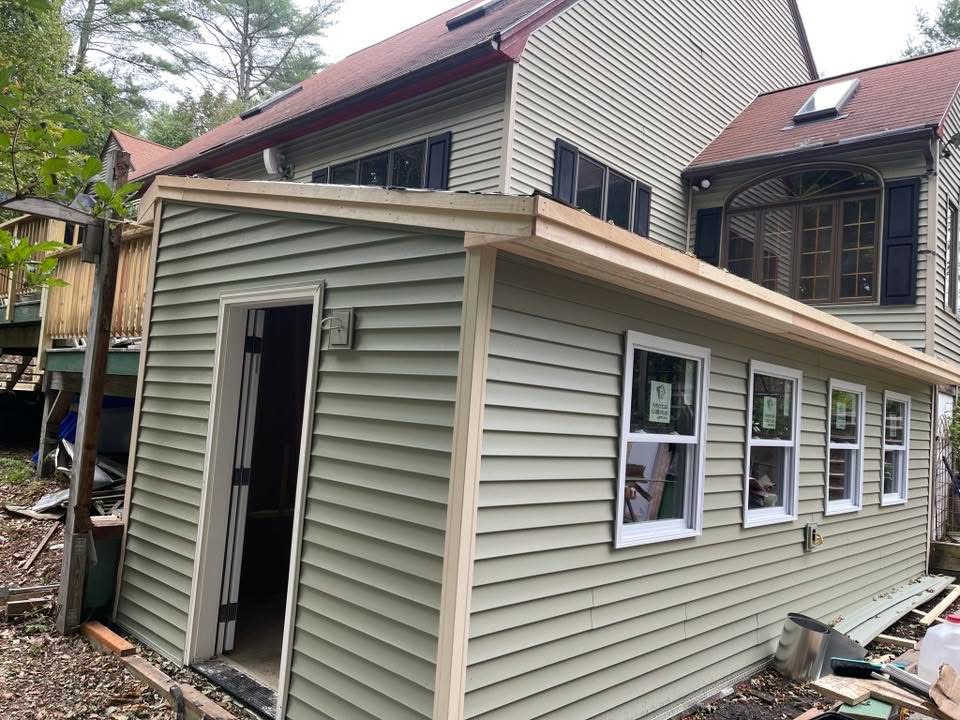Exterior extension clad in horizontal siding with white window trim
