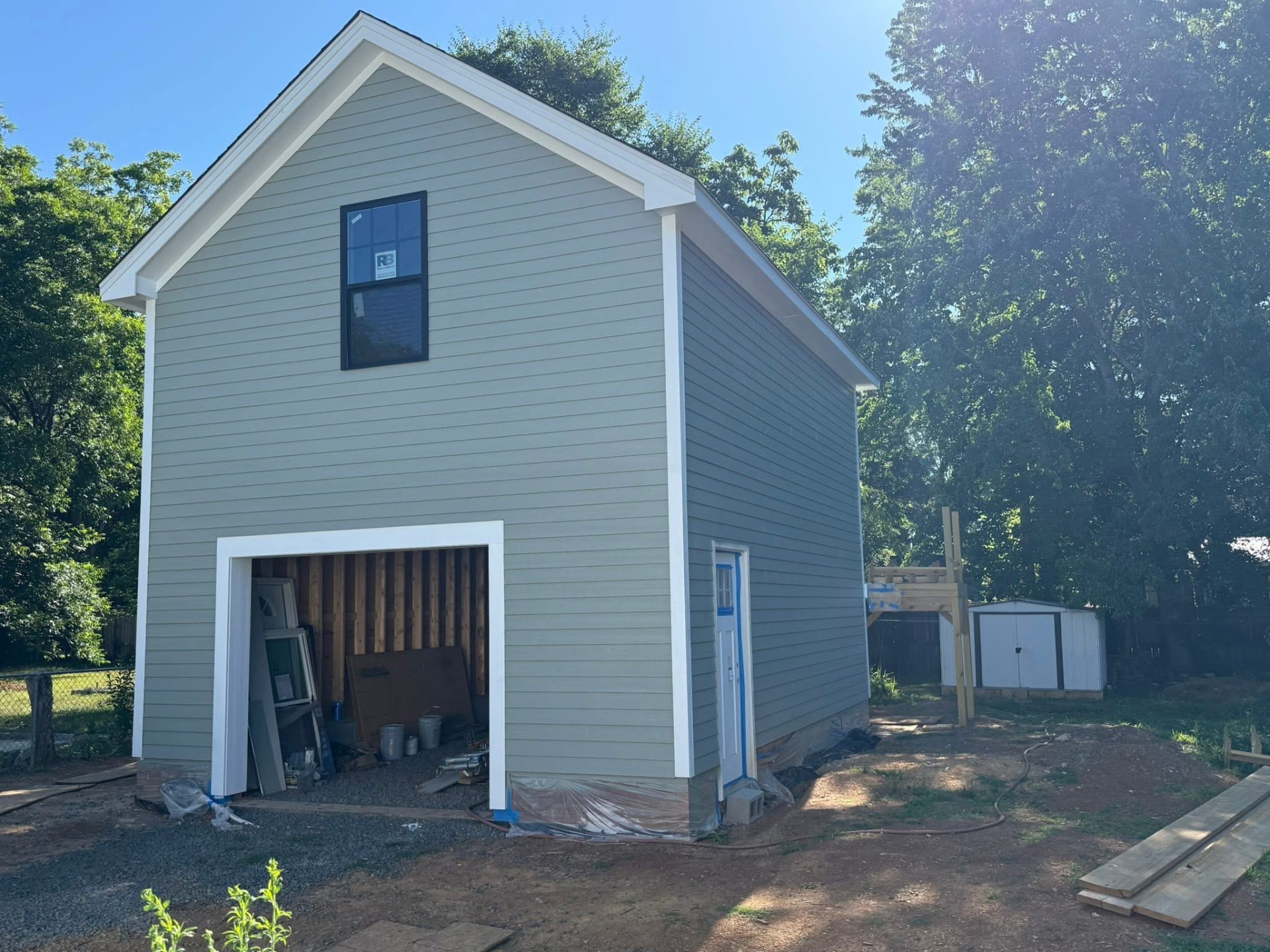 Two-story addition exterior with light gray siding, white trim, and an upper window