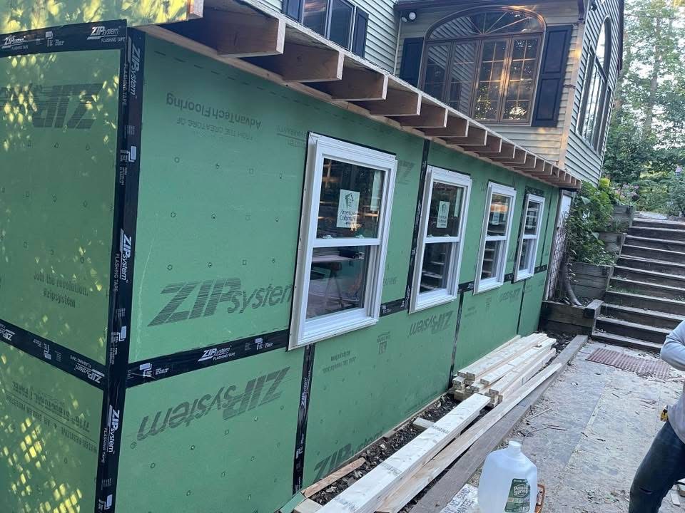 Exterior extension with green wall sheathing and installed windows before siding