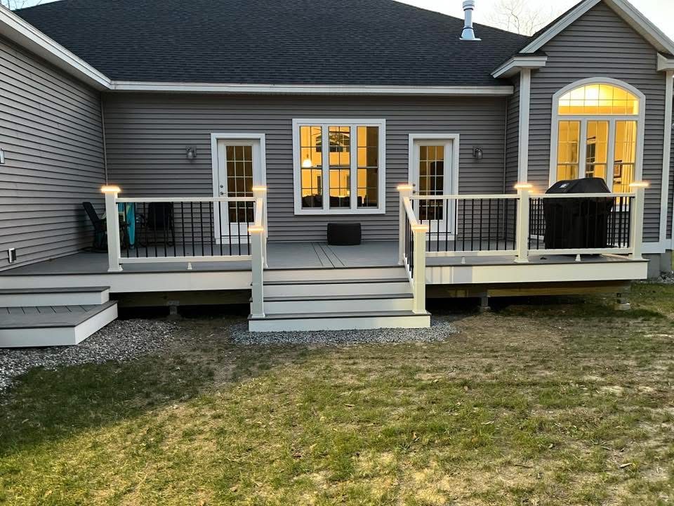 Finished deck with gray boards, white railings, black balusters, and illuminated post caps