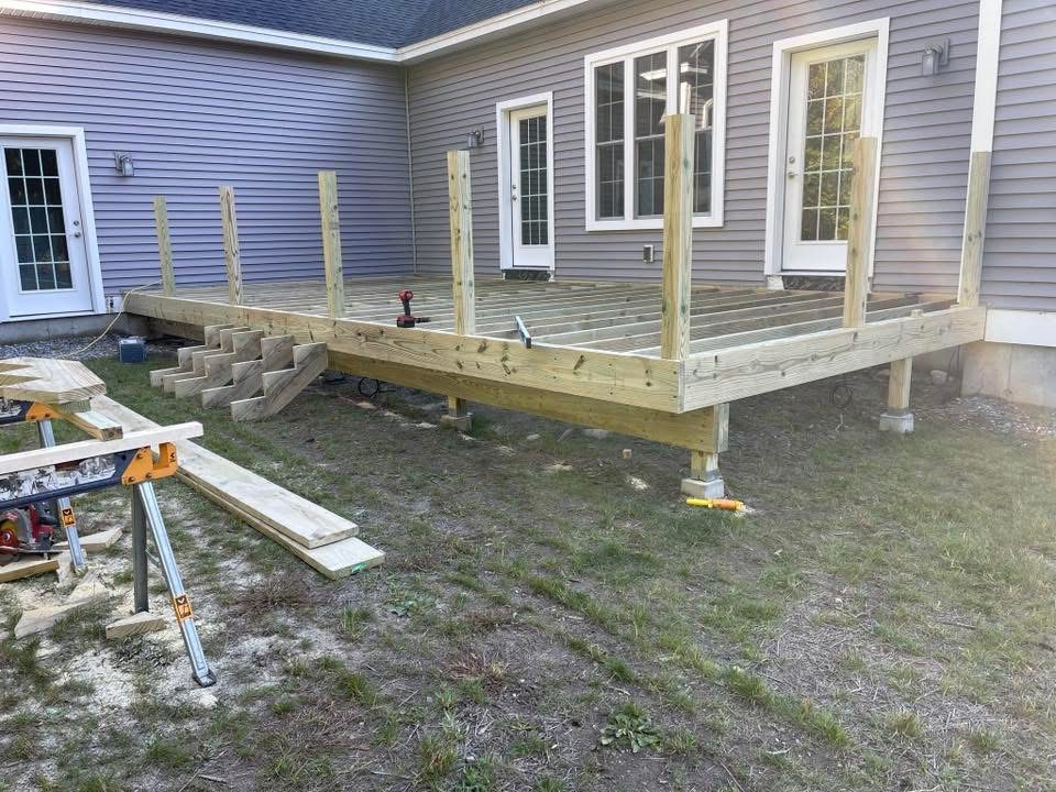 Pressure-treated deck framing and posts beside a gray-sided home