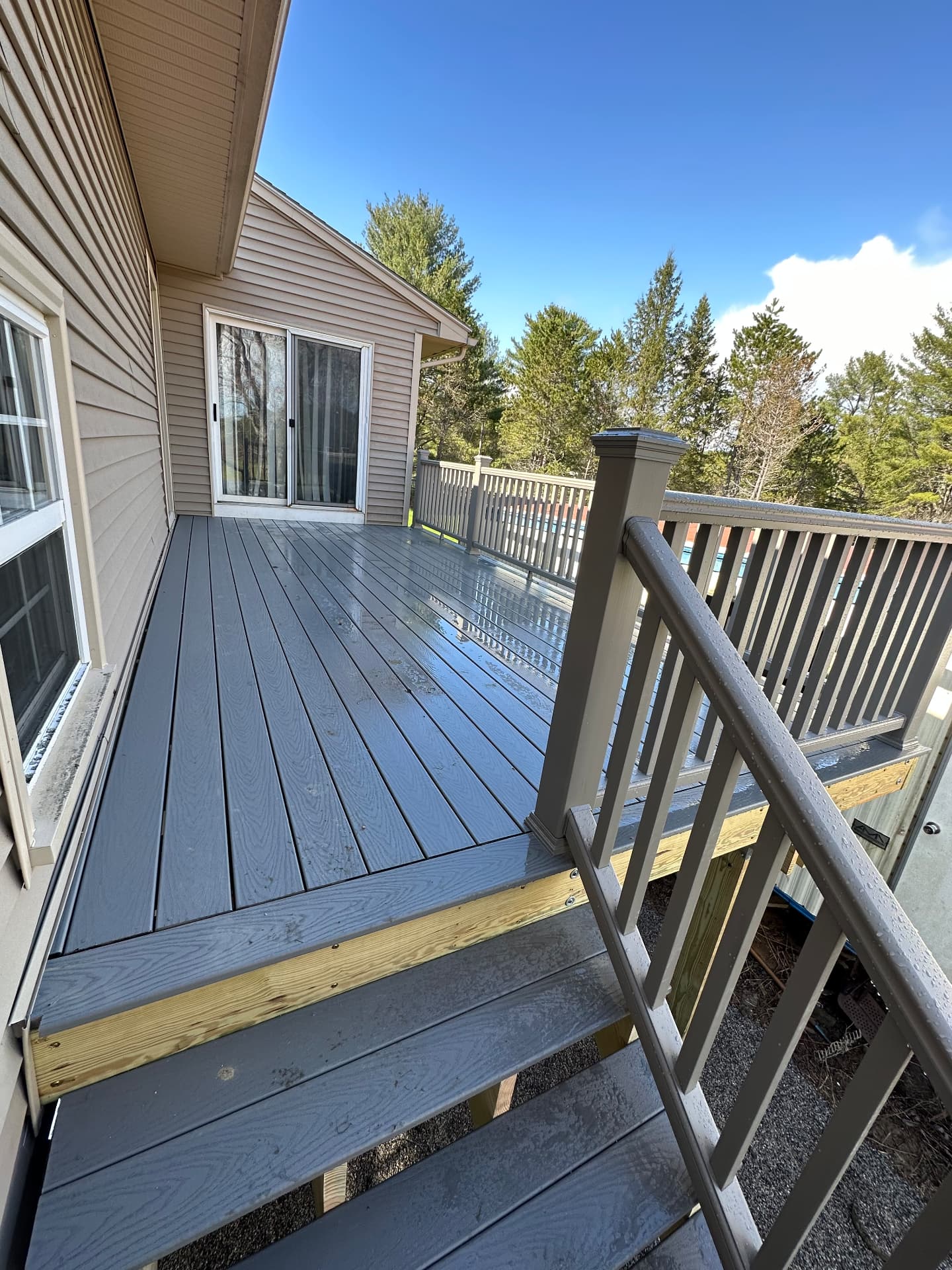 Gray composite deck stairs and railings leading up to a sliding glass door
