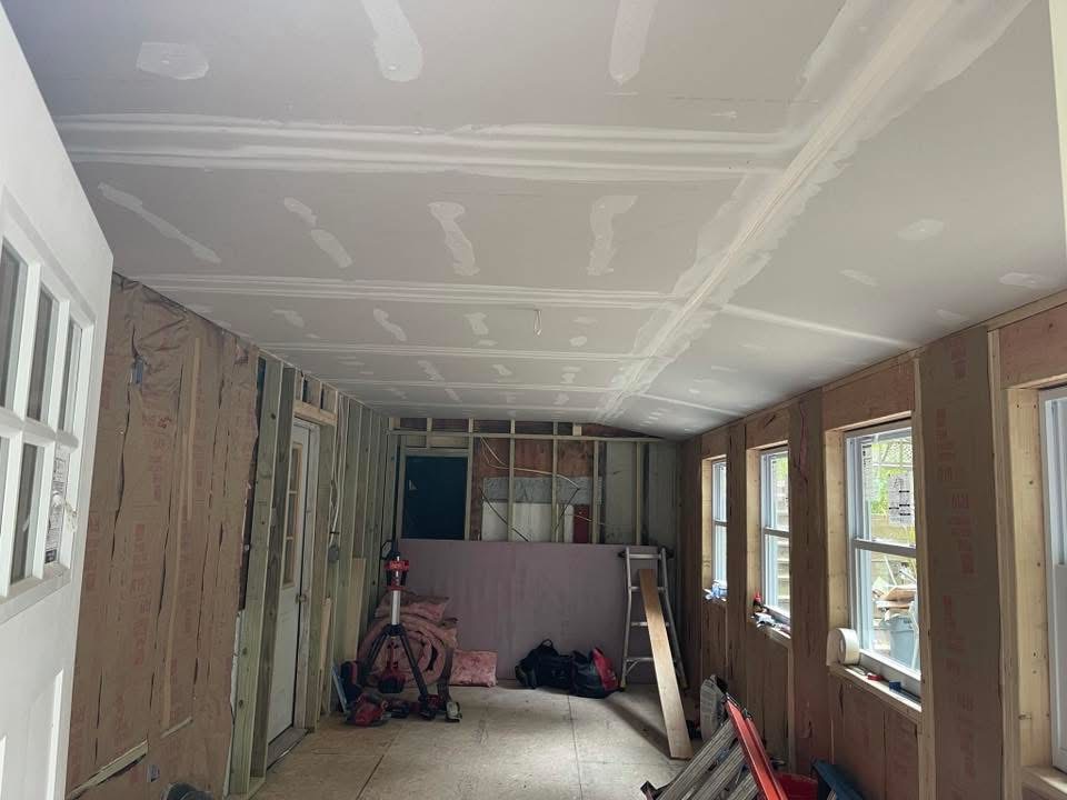 Room renovation with exposed wall studs, unfinished drywall, and subfloor