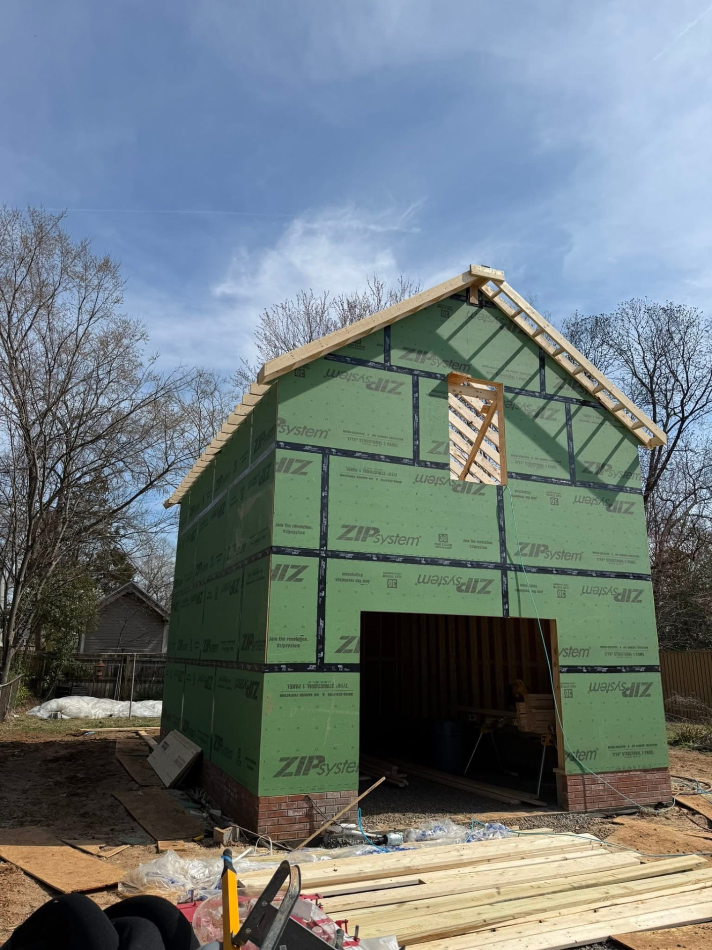 Two-story addition with exposed green sheathing and roof framing