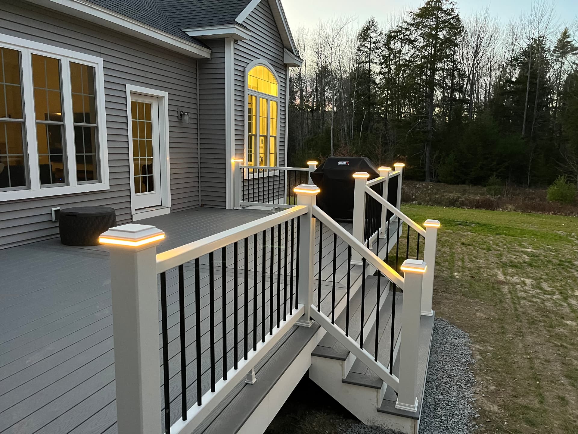 Finished composite deck with white railings and lit post caps built by Rock River Construction in Wake Forest, NC